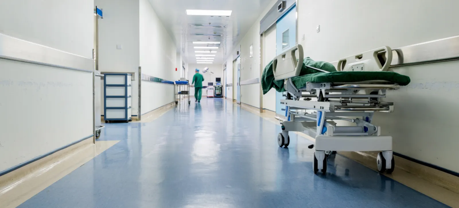 Pasillo hospitalario con camilla y piso vinílico, espacio de salud diseñado y adecuado bajo normativa sanitaria