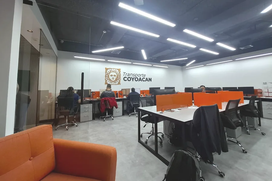 Oficinas remodeladas con puestos de trabajo, techo negro con iluminación LED y oficina cerrada en vidrio